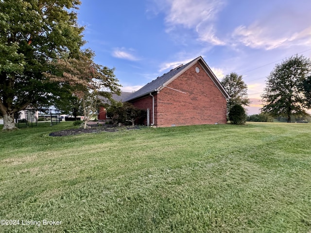 property exterior at dusk featuring a yard