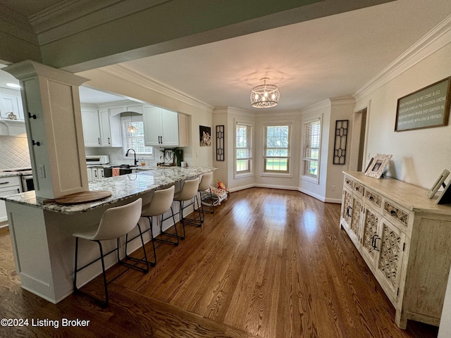 kitchen featuring backsplash, dark wood-type flooring, white cabinets, light stone counters, and a chandelier