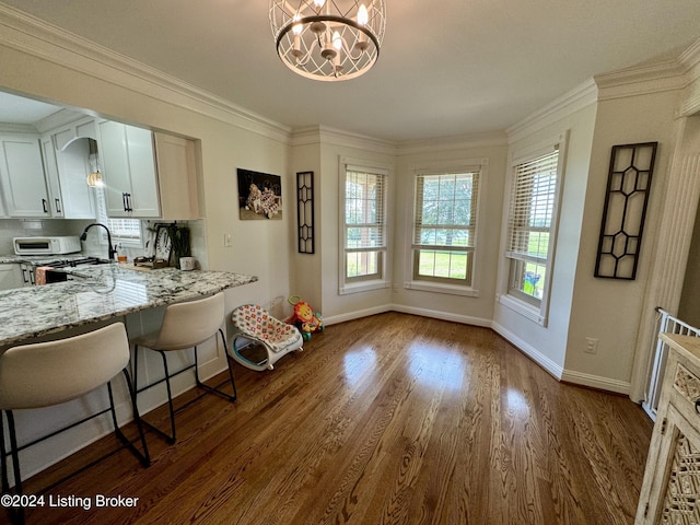 kitchen featuring white cabinets, a breakfast bar, dark hardwood / wood-style floors, and ornamental molding