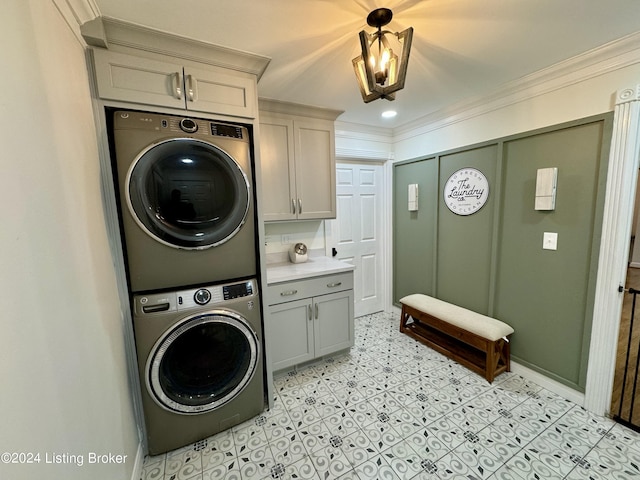 clothes washing area featuring cabinets, stacked washer / drying machine, and ornamental molding