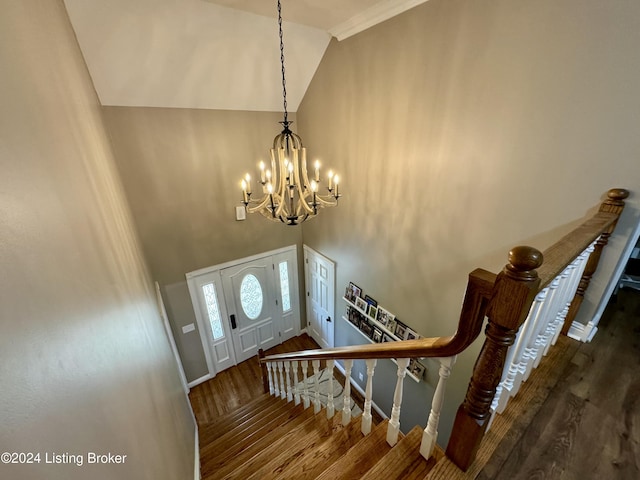 foyer featuring ornamental molding, dark wood-type flooring, high vaulted ceiling, and a chandelier