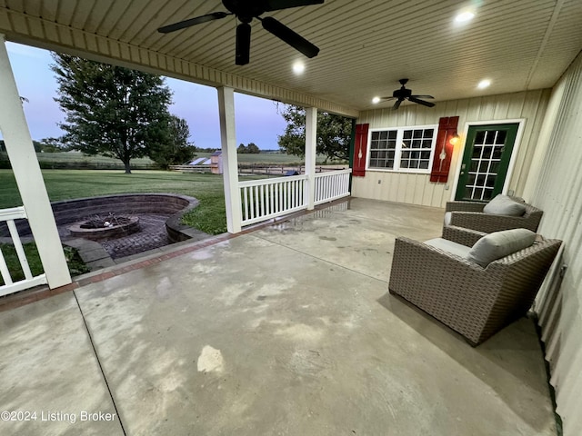 patio terrace at dusk featuring ceiling fan, a porch, and an outdoor fire pit