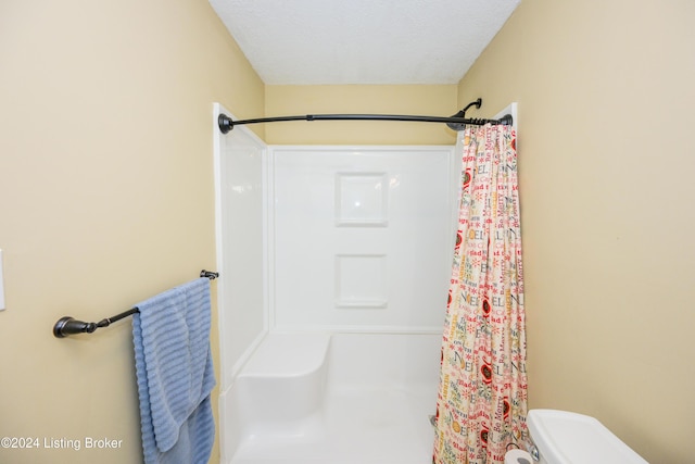 bathroom with a shower with curtain, a textured ceiling, and toilet