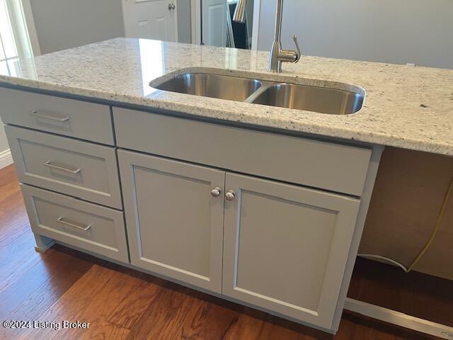 kitchen with gray cabinetry, light stone countertops, dark hardwood / wood-style flooring, and sink