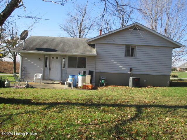 back of property with a lawn and central AC