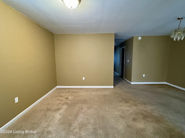 carpeted spare room featuring a notable chandelier