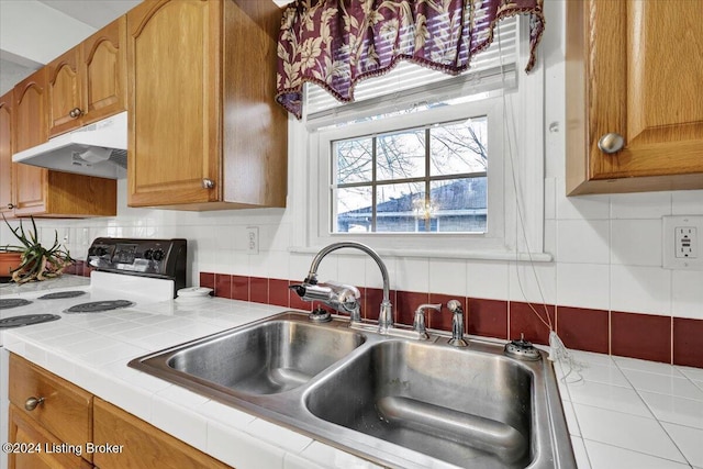 kitchen with tasteful backsplash, range with electric cooktop, sink, and tile counters