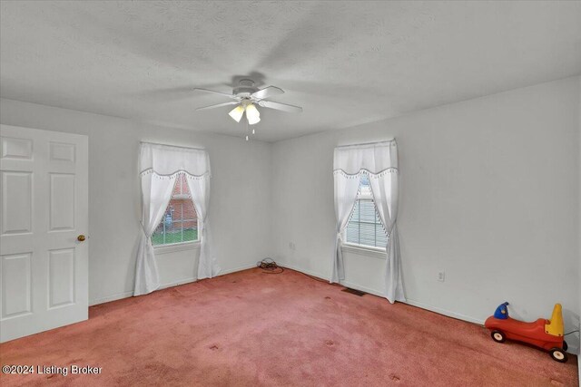 carpeted empty room featuring ceiling fan and a textured ceiling