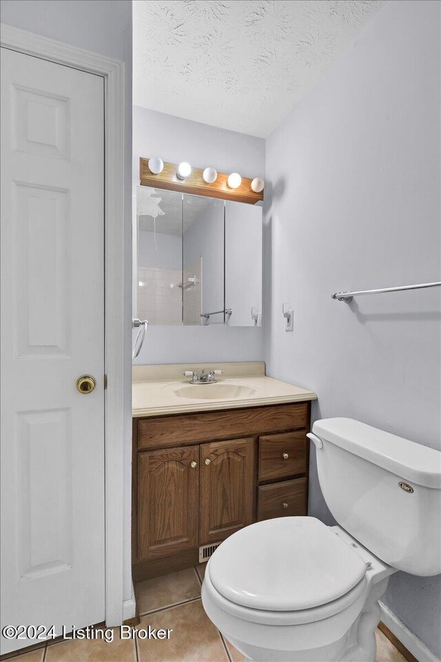 bathroom featuring vanity, tile patterned floors, a textured ceiling, and toilet