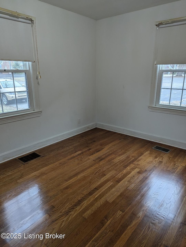 spare room with a healthy amount of sunlight and dark hardwood / wood-style floors