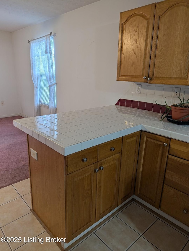 kitchen featuring light tile patterned floors, tile countertops, and kitchen peninsula