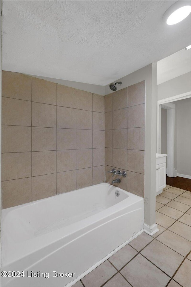 bathroom featuring tile patterned floors, vanity, a textured ceiling, and tiled shower / bath