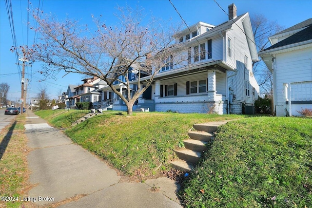 view of front of house with a front lawn and central air condition unit