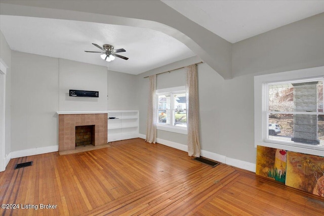 unfurnished living room featuring a fireplace, wood-type flooring, and ceiling fan