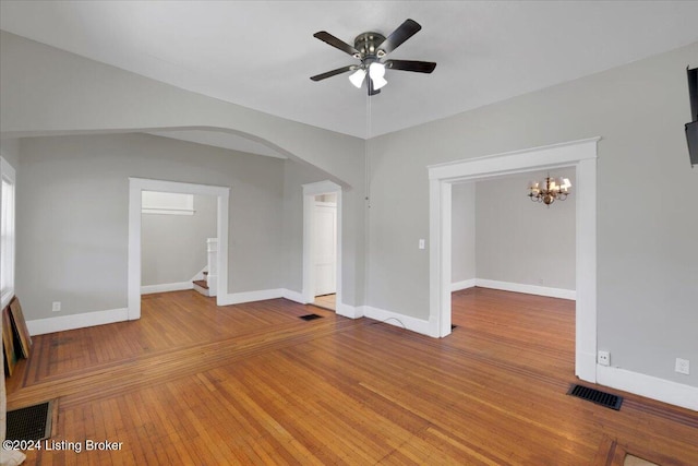 unfurnished living room with ceiling fan with notable chandelier and hardwood / wood-style flooring