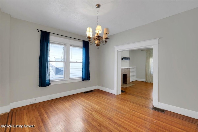 unfurnished dining area with a notable chandelier and wood-type flooring