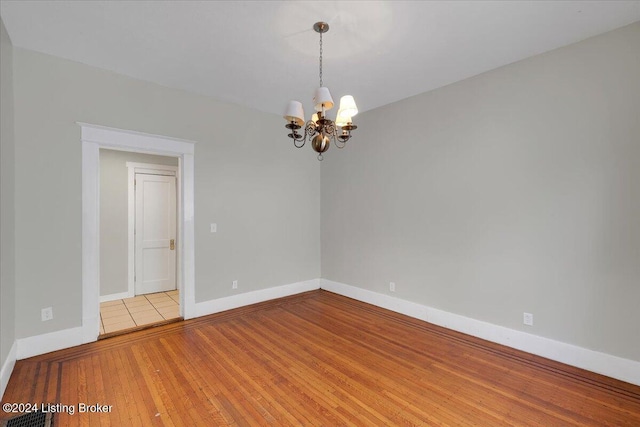 empty room featuring a chandelier and light hardwood / wood-style flooring