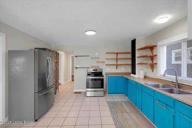 kitchen featuring appliances with stainless steel finishes, a textured ceiling, sink, blue cabinetry, and light tile patterned floors