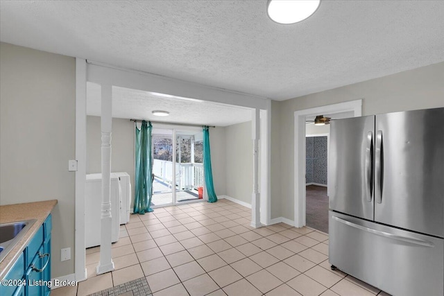 kitchen featuring stainless steel fridge, a textured ceiling, ceiling fan, light tile patterned floors, and washer / clothes dryer