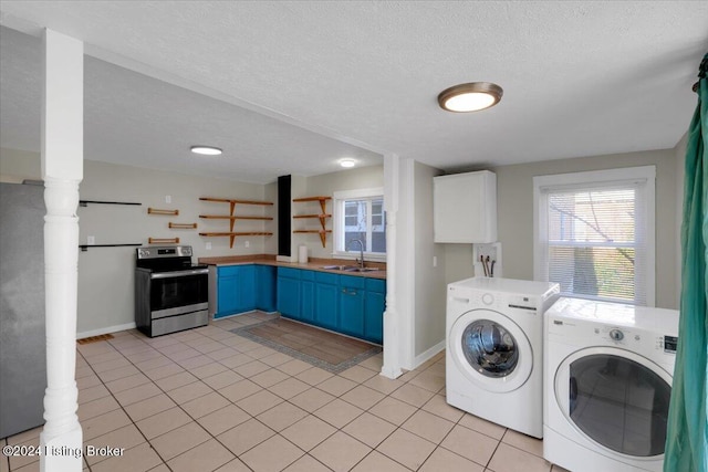 laundry area with washer and clothes dryer, sink, light tile patterned floors, and a textured ceiling