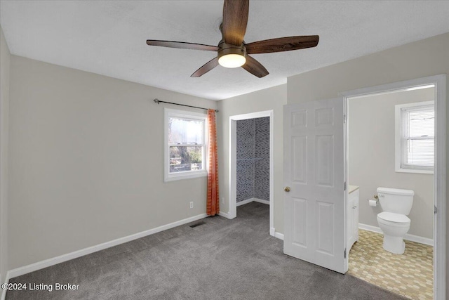 unfurnished bedroom with ensuite bath, ceiling fan, a closet, and carpet floors