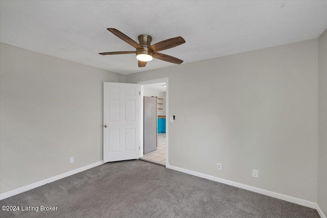 unfurnished room featuring ceiling fan, light colored carpet, and a textured ceiling