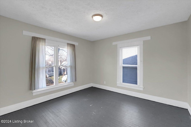 spare room with a textured ceiling and dark wood-type flooring