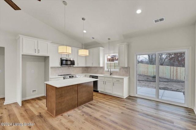 kitchen featuring a center island, lofted ceiling, white cabinets, appliances with stainless steel finishes, and light hardwood / wood-style floors