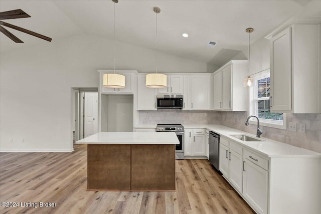 kitchen featuring sink, pendant lighting, vaulted ceiling, white cabinets, and appliances with stainless steel finishes