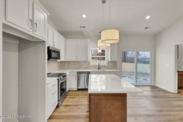 kitchen featuring sink, hanging light fixtures, stainless steel appliances, light hardwood / wood-style floors, and white cabinets