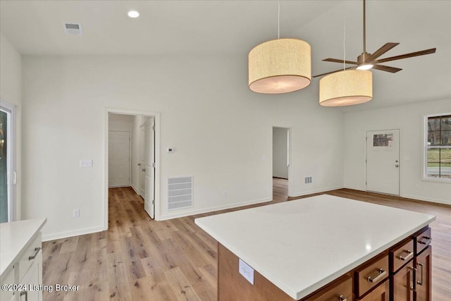 kitchen featuring light wood-type flooring, high vaulted ceiling, hanging light fixtures, and ceiling fan