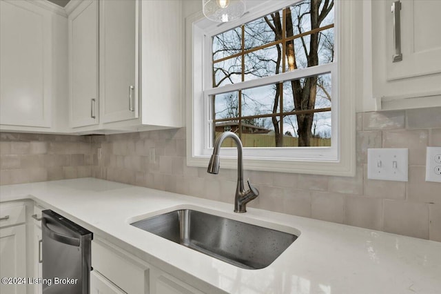 kitchen featuring white cabinets, backsplash, dishwasher, and sink