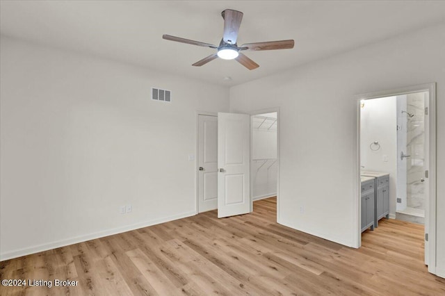 unfurnished bedroom featuring a walk in closet, ensuite bath, ceiling fan, light hardwood / wood-style floors, and a closet