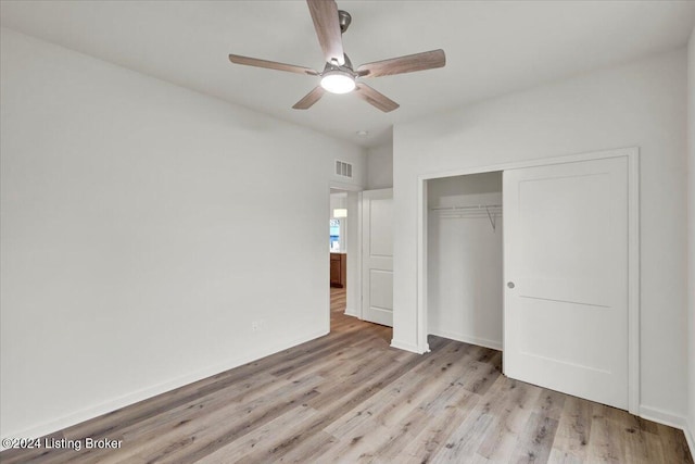 unfurnished bedroom with ceiling fan, light wood-type flooring, and a closet