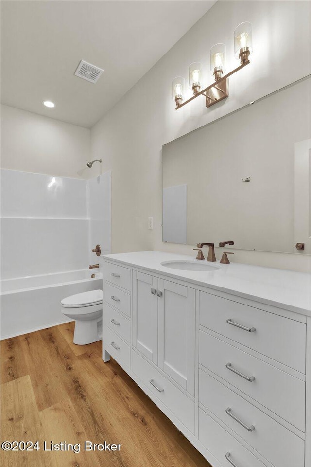 full bathroom with wood-type flooring, vanity, bathing tub / shower combination, and toilet