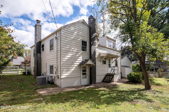 rear view of house with a yard and central AC