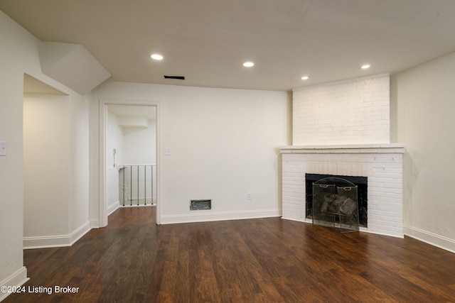 unfurnished living room with dark hardwood / wood-style flooring and a brick fireplace