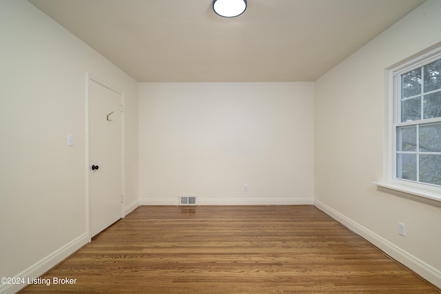 spare room featuring wood-type flooring and a healthy amount of sunlight