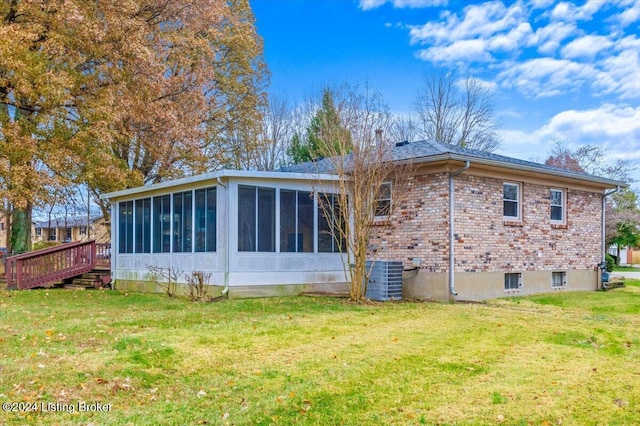 rear view of property with a lawn, a sunroom, and cooling unit