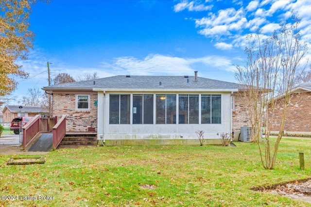 rear view of house with a lawn, cooling unit, and a sunroom