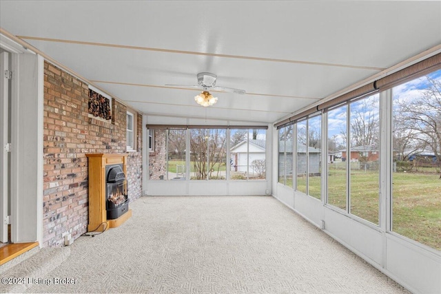 unfurnished sunroom with ceiling fan and a wood stove