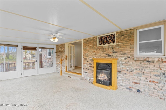 unfurnished living room with ceiling fan, carpet, and brick wall