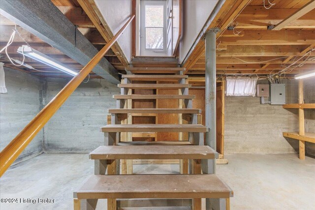 stairway with electric panel and concrete floors