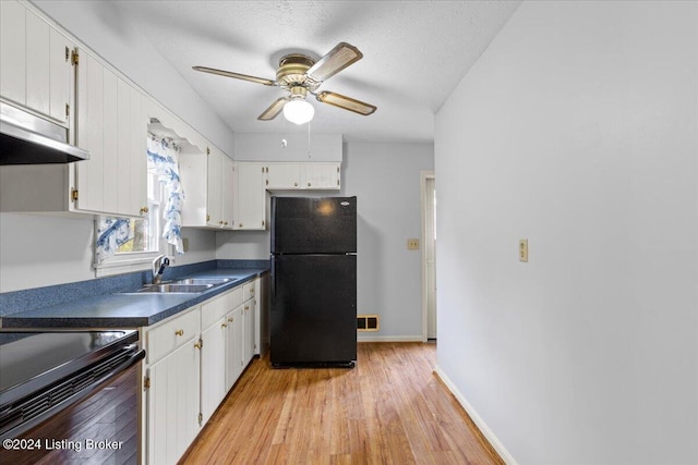 kitchen with light wood-type flooring, white cabinetry, black fridge, and sink