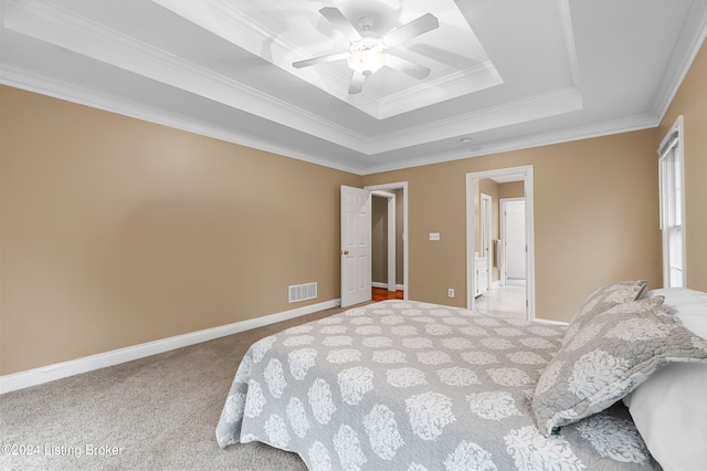 carpeted bedroom featuring ceiling fan, ornamental molding, and a tray ceiling