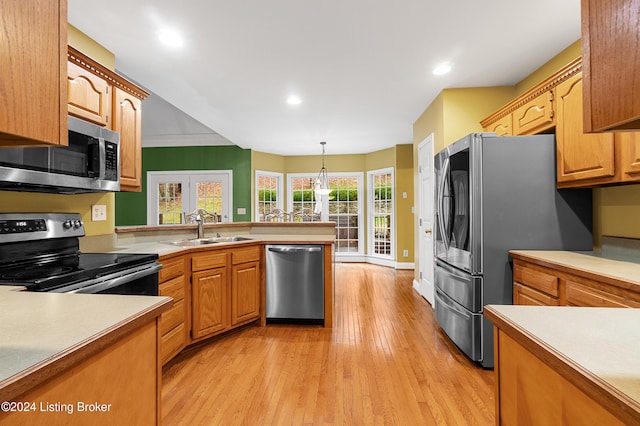 kitchen with sink, ornamental molding, decorative light fixtures, light hardwood / wood-style floors, and stainless steel appliances