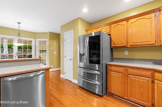 kitchen with light wood-type flooring, hanging light fixtures, and appliances with stainless steel finishes