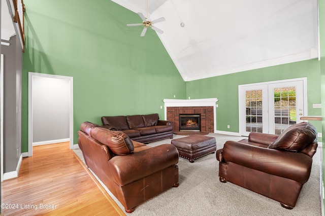 living room featuring high vaulted ceiling, crown molding, a brick fireplace, ceiling fan, and wood-type flooring