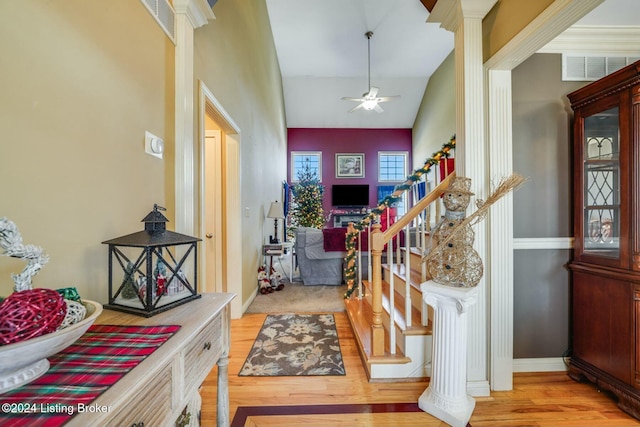 foyer entrance with light hardwood / wood-style floors, ornate columns, ceiling fan, and lofted ceiling