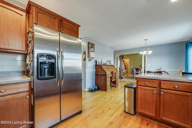 kitchen featuring tasteful backsplash, an inviting chandelier, stainless steel fridge with ice dispenser, light hardwood / wood-style floors, and hanging light fixtures